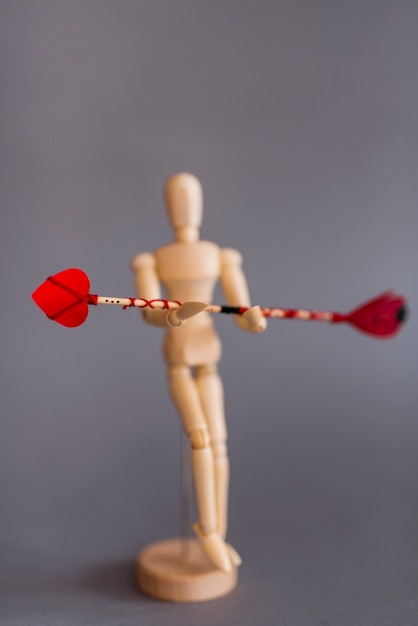 Wooden mannequin holding red love arrow