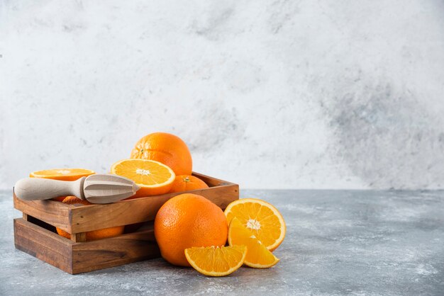 A wooden old box full of juicy orange fruit on stone table .