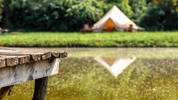 Free Photo wooden pier for rest near a lake with tent on the background at glamping. nature, greenery around