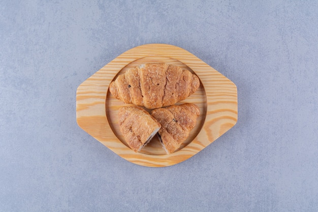 A wooden plate of croissants with delicious chocolate . 