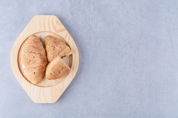 A wooden plate of croissants with delicious chocolate . 