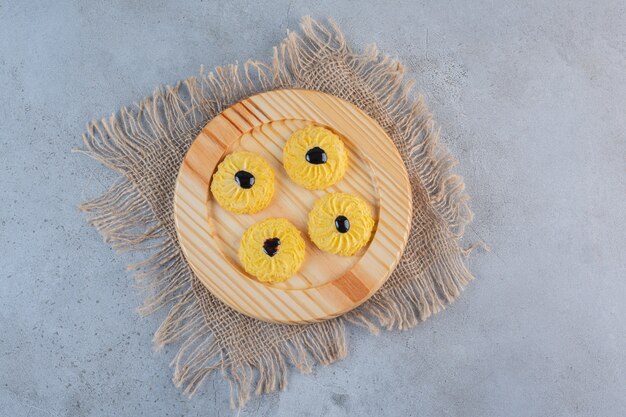 A wooden plate of delicious round biscuit on stone.