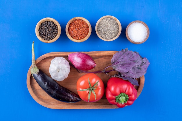 Wooden plate of fresh ripe vegetables with various spices