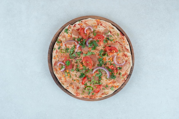 A wooden plate of pita bread with sliced tomato and onion.