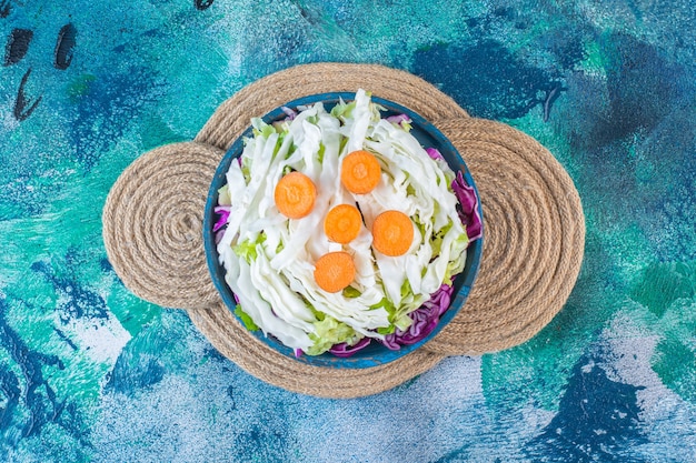 A wooden plate of various vegetables on a trivet 