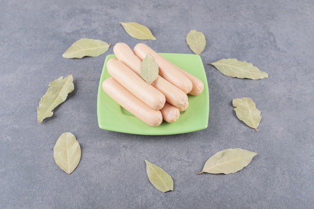 Free photo a wooden plate with boiled sausages and bay leaves