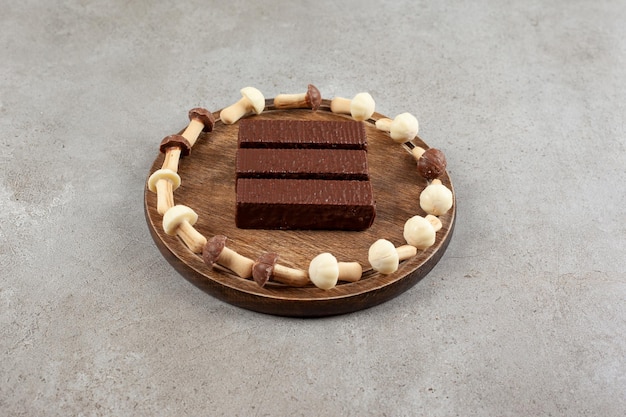 A wooden plate with chocolates and wooden bowl with sweet mushrooms.