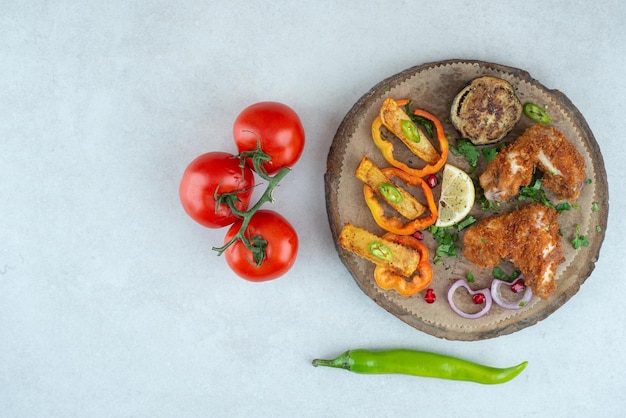 Free Photo a wooden plate with peppers and tomatoes on white