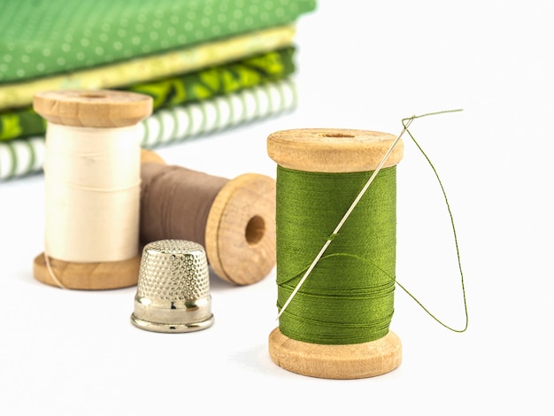 Wooden spool of thread embroidery set with cloth over white background