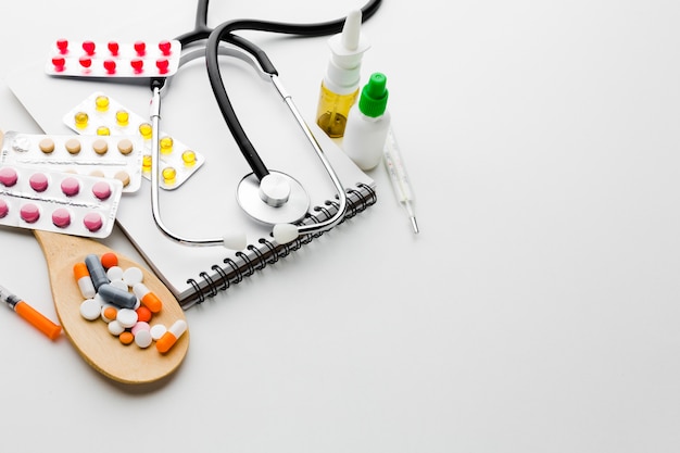 Wooden spoon filled with pills and stethoscope