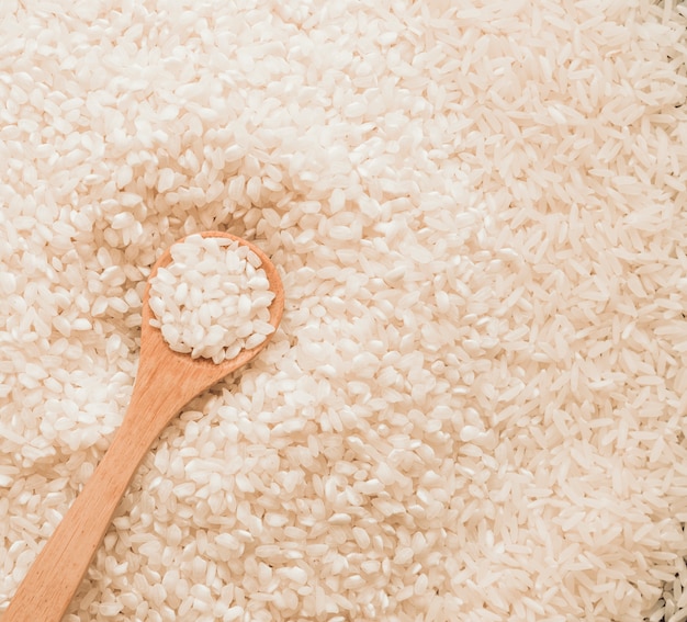 Wooden spoon in uncooked white rice grains