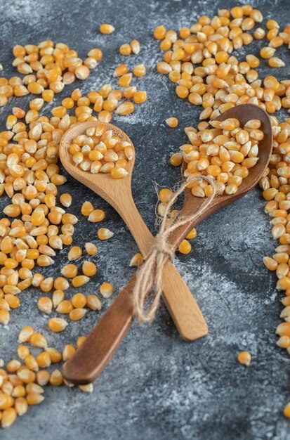 Wooden spoons of sweet corns on marble surface.