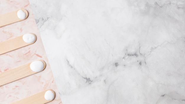 Wooden sticks with cream on marble background