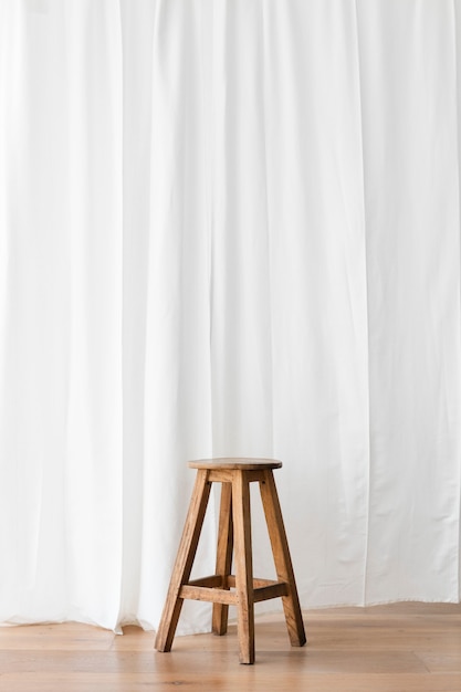 Free photo wooden stool in front of a white curtain