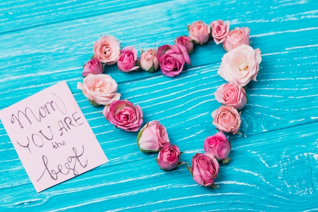 Free photo wooden surface with card and floral heart for mother's day