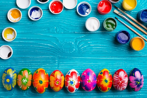 Wooden surface with paint jars and easter eggs in row