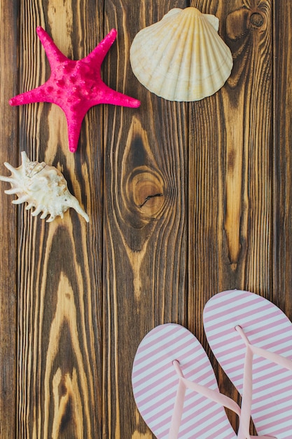 Free photo wooden surface with seashells and flip flops