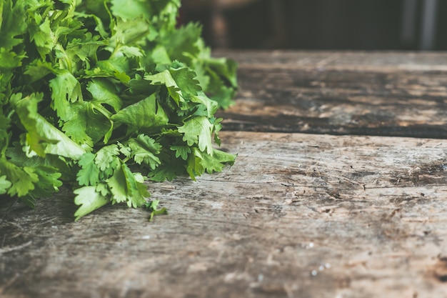 Wooden surface with space for text with green parsley leaves on the side