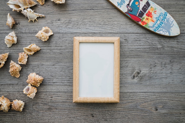 Free Photo wooden surface with surfboard, frame and seashells