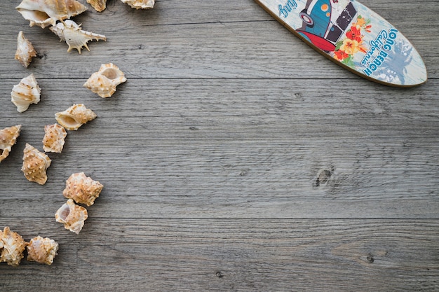 Free photo wooden surface with surfboard and seashells