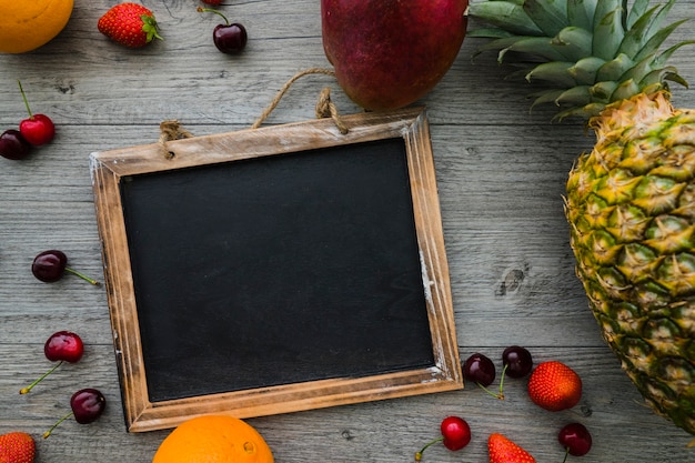 Wooden surface with variety of fruits and blank slate