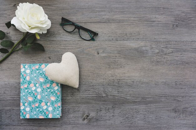 Wooden surface with white flower, book and heart