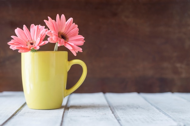 Free photo wooden table with pretty flowers on yellow mug