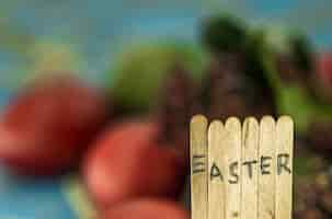 Free photo the word easter in the conceptual block text on wooden sticks, beautiful festive eggs with greens