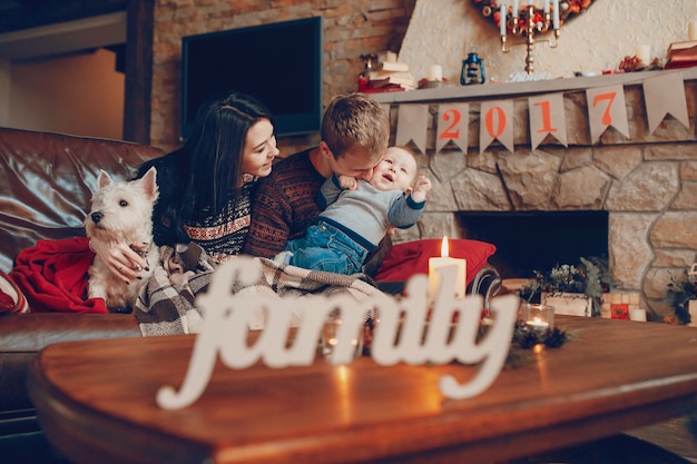 Free Photo word "family" with a family sitting on the sofa in the background on christmas