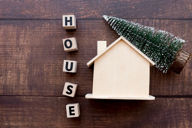 Word house blocks with wooden house and christmas tree on table