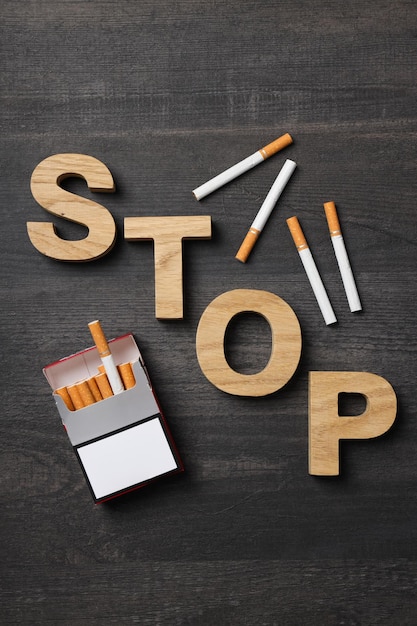 Free photo the word stop with a pack of cigarettes on a dark background