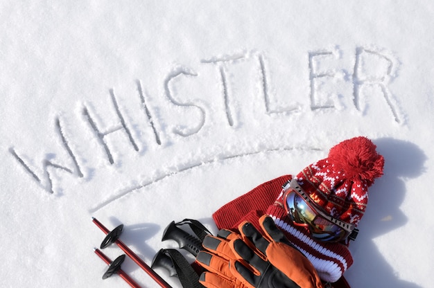 Free Photo the word whistler written in snow with ski poles, goggles and hats 