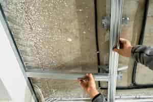 Free photo worker adjusts a metal profile for mounting a plasterboard ceiling frame, close-up, selective focus on the hands of a specialist. industrial renovation and renovation