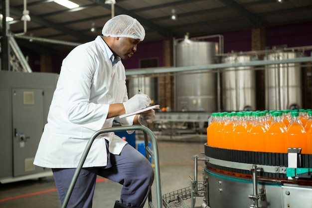 Free Photo worker checking bottles in juice factory