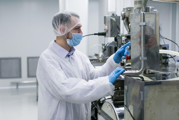 Worker on factory in white suit working with manufacture machine