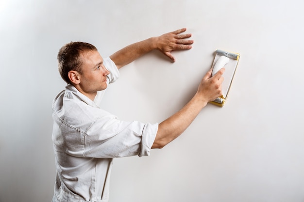 Free Photo worker grinding white wall with sandpaper.