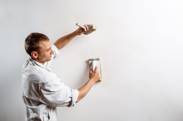 Free Photo worker grinding white wall with sandpaper.