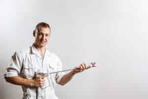 Free photo worker holding spray gun on white wall.