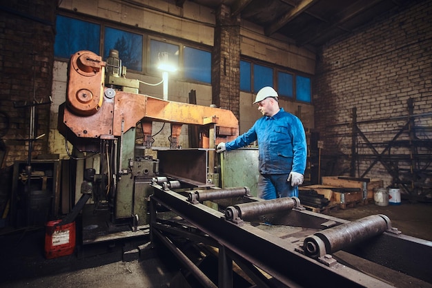 Free photo worker is controlling a process of rail cutting at busy metal factory.