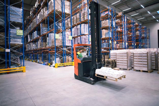 Free Photo worker operating forklift machine and relocating goods in large warehouse center