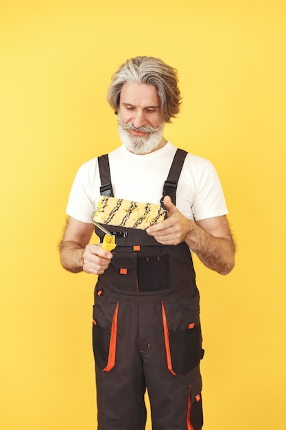 Free photo worker in overalls. man with tools. senior with paint roller.