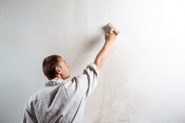 Free Photo worker painting wall with brush in white color.