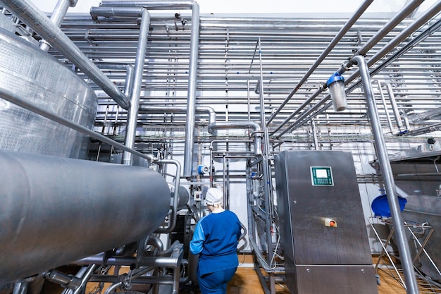 Free photo worker of production department make set up of the line while standing near equipment of dairy factory