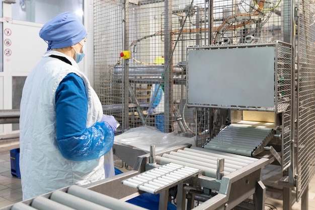 Free photo worker of production department make set up of the line while standing near equipment of dairy factory