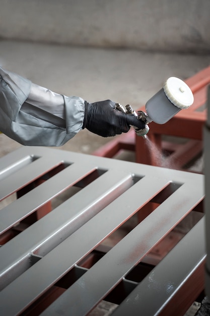 Free photo worker spraying powder paint from a gun side view