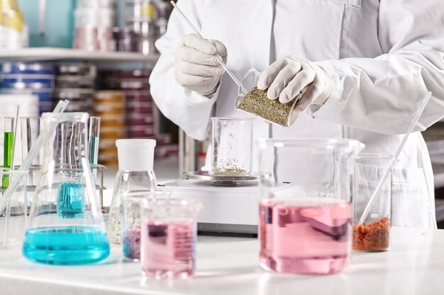 Worker surrounded with glass beakers filled with colorful liquid