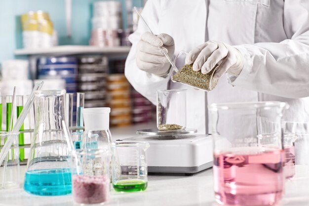 Worker surrounded with glass beakers filled with colorful liquid