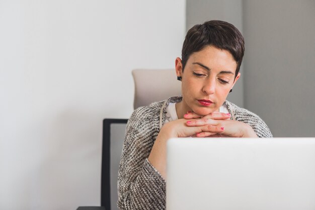 Worker thinking with hands under her chin