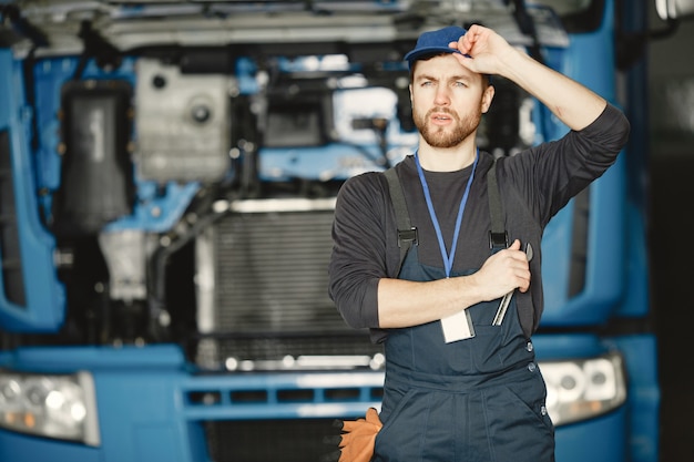 Worker in uniform. Man repairs a truck. Man with tools