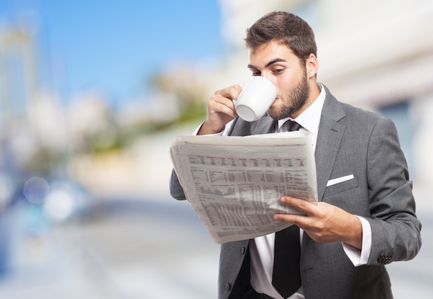 Free Photo worker with cup of coffee reading the news